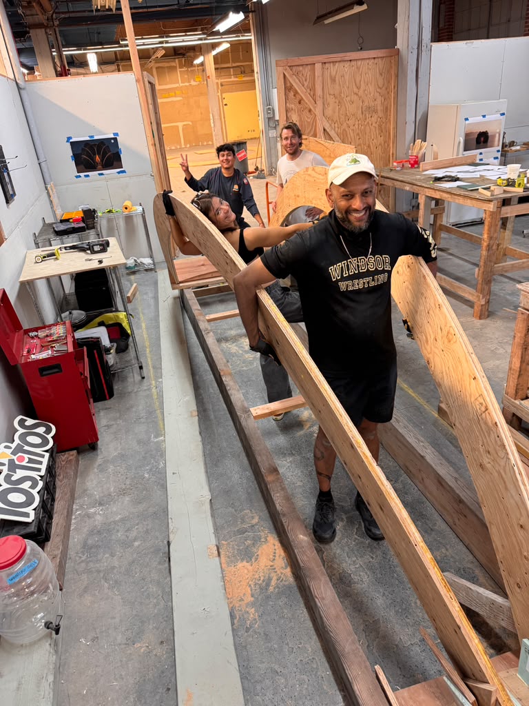 Build team smiling while carrying a wooden rib