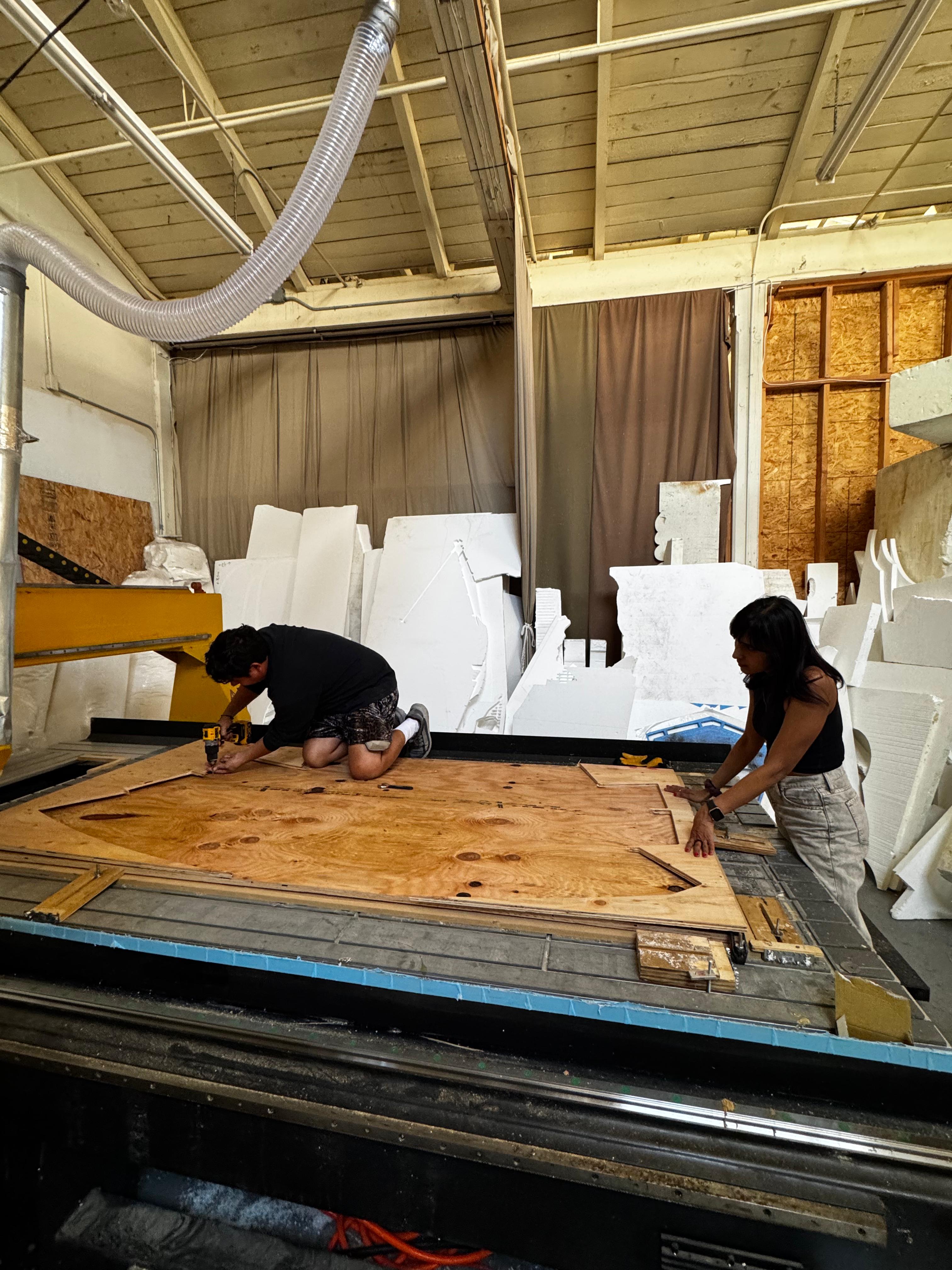 Two builders working on a large plywood component